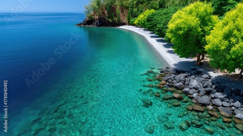 Turquoise Water Meets Rocky Shoreline With Lush Green Trees On A Sunny Day In A Tropical Bay