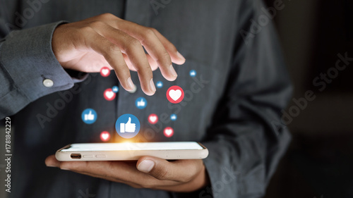 Hand using smartphone with floating social media icons, digital marketing and communication concept