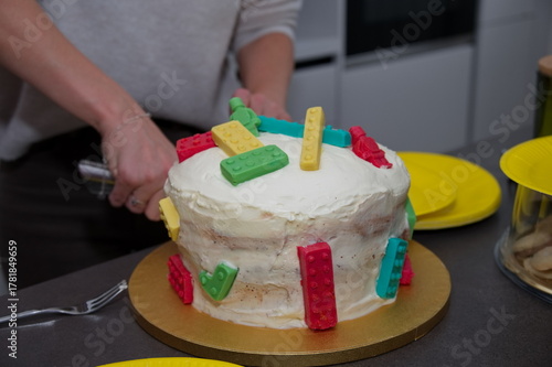 Closeup of child's birthday cake. Woman's hands cutting it