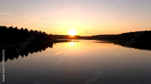 Aerial view of a tranquil lake at sunrise, with golden sunlight creating dazzling optical reflections on the water's surface picturesque, environment, dazzling