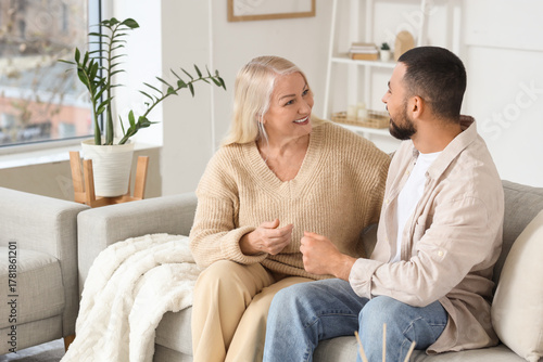 Young man hugging his mother on sofa at home