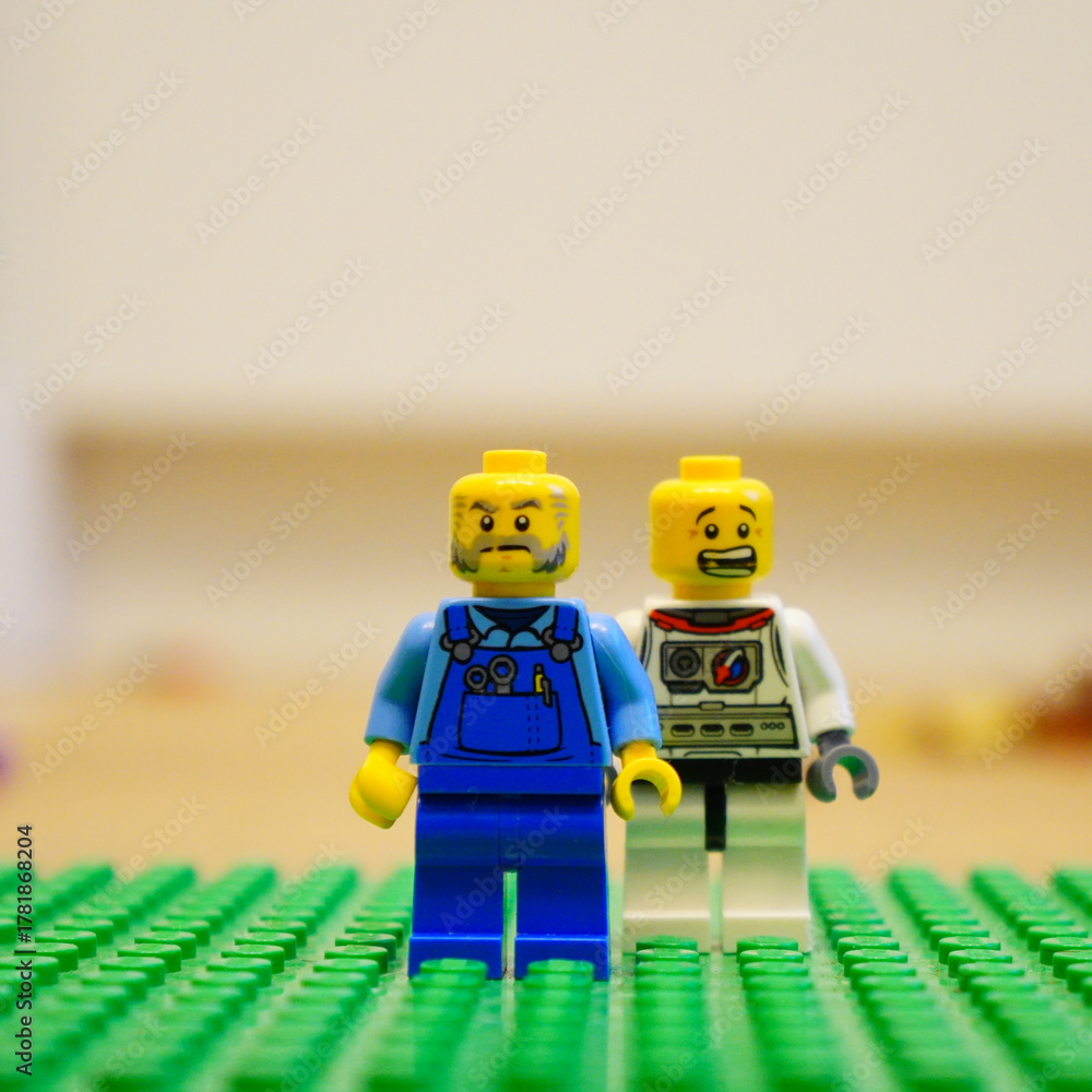 Fototapeta premium Lego minifigures of a farmer and an astronaut standing together on a green baseplate