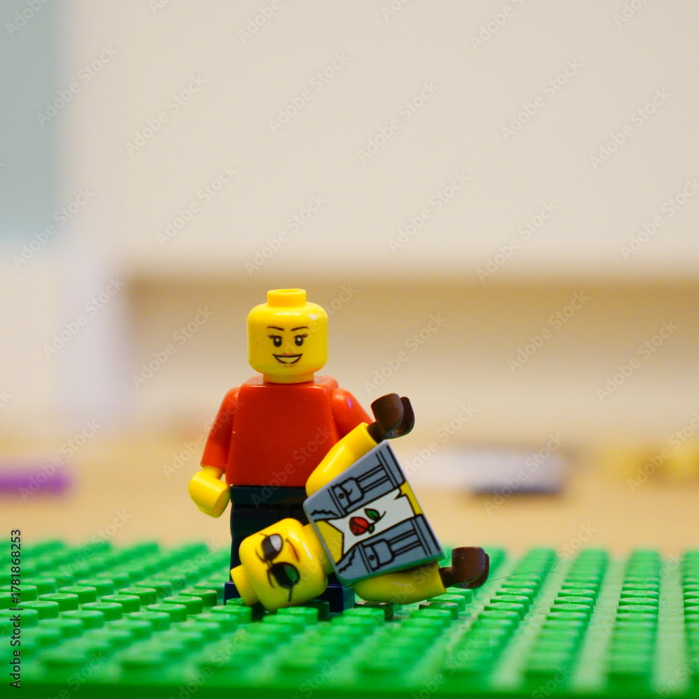 Obraz premium Lego minifigure with another minifigure lying on a green baseplate