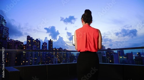 Young beautiful asian businesswoman with laptop on the building rooftop at city night
