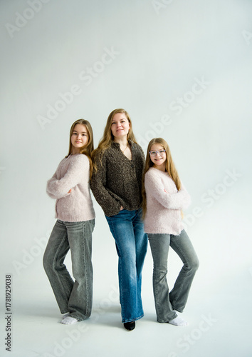 portrait of beautiful blonde smiling mother and daughter with long hair posing in white studio