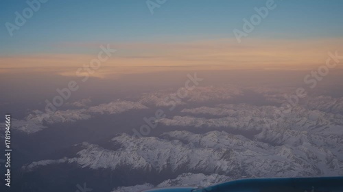Sunset View Over Snow-Covered Mountains from Plane