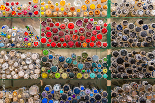 Colorful buttons in transparent tubes, neatly sorted by color and shape, create a vibrant pattern on a shop wall