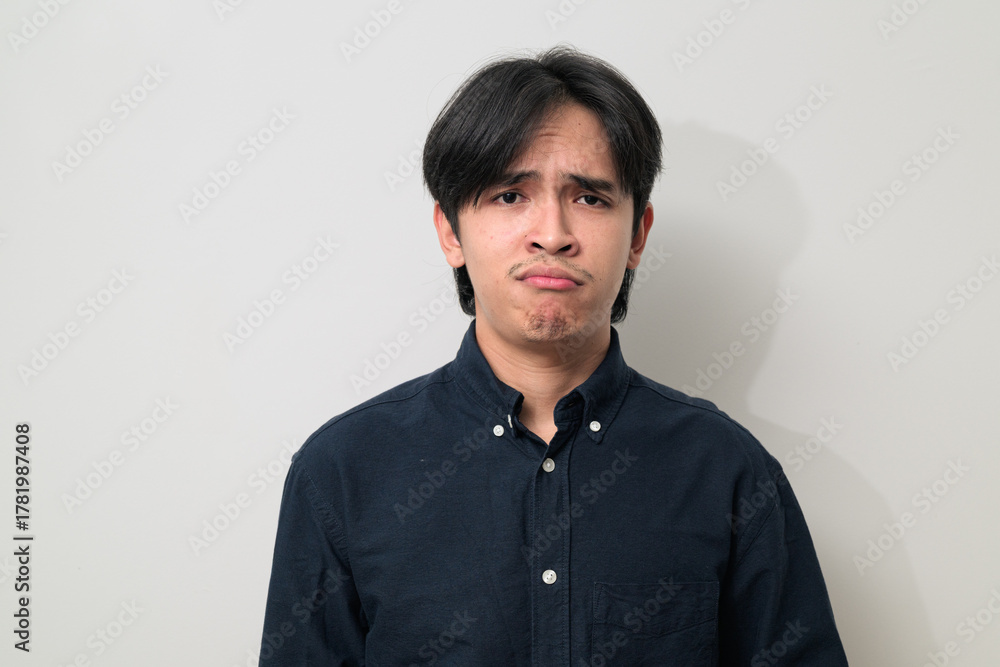 Obraz premium Portrait of handsome Young Asian Thai man looking frustrated and bored against white background