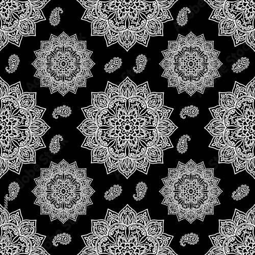 Intricate white mandala and paisley ornaments create a seamless pattern on a black background
