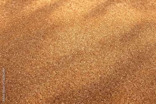 Close-up image of a textured golden sand surface with soft shadows and slight unevenness