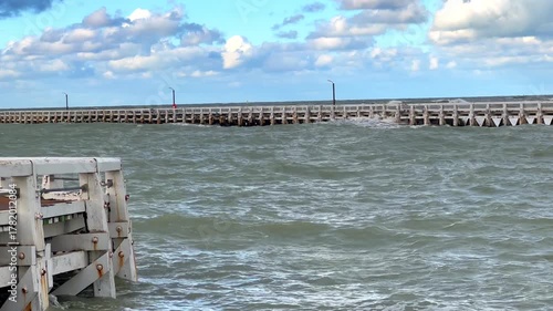 Stormy ocean scene, Fierce ocean waves batter coastline as port activities persist amidst stormy maritime conditions