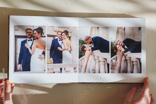 Female hands flipping through a photo book with wedding photos on a white table