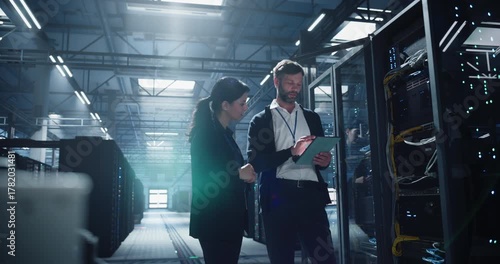 Engineer inspects server rack with tablet in a bright data center, cables, network devices, device monitoring, connection checks, IT service for business infrastructure and secure data management.