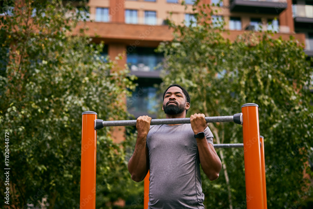 Obraz premium Everyday African Man Sets Weight Loss Goal With Outdoor Pull-Up Workout