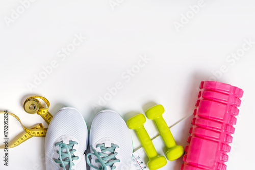 Sporty flat lay with sneakers, dumbbells, avocado on a white isolated background
