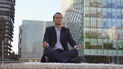 Businessman meditating in lotus position in a modern city