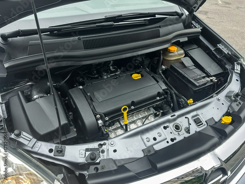 Engine bay exposed with intricate machinery showcasing mechanical precision in a modern car at a busy garage during the day