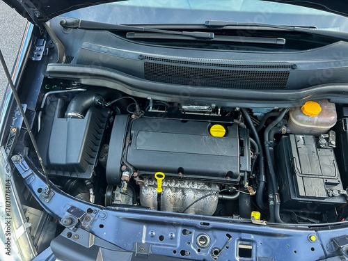 Under the hood of a compact car showing the inner workings of the engine during a bright daylight inspection on a road trip