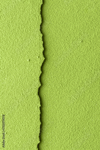 Textured green matcha powder split by narrow seam at center on vertical frame, versatile background for food branding and packaging.