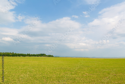 PASAK CHONLASIT DAM, LOPBURI, THAILAND Expansive green meadow and campground area next to the reservoir, a popular tourist destination and relaxation spot.