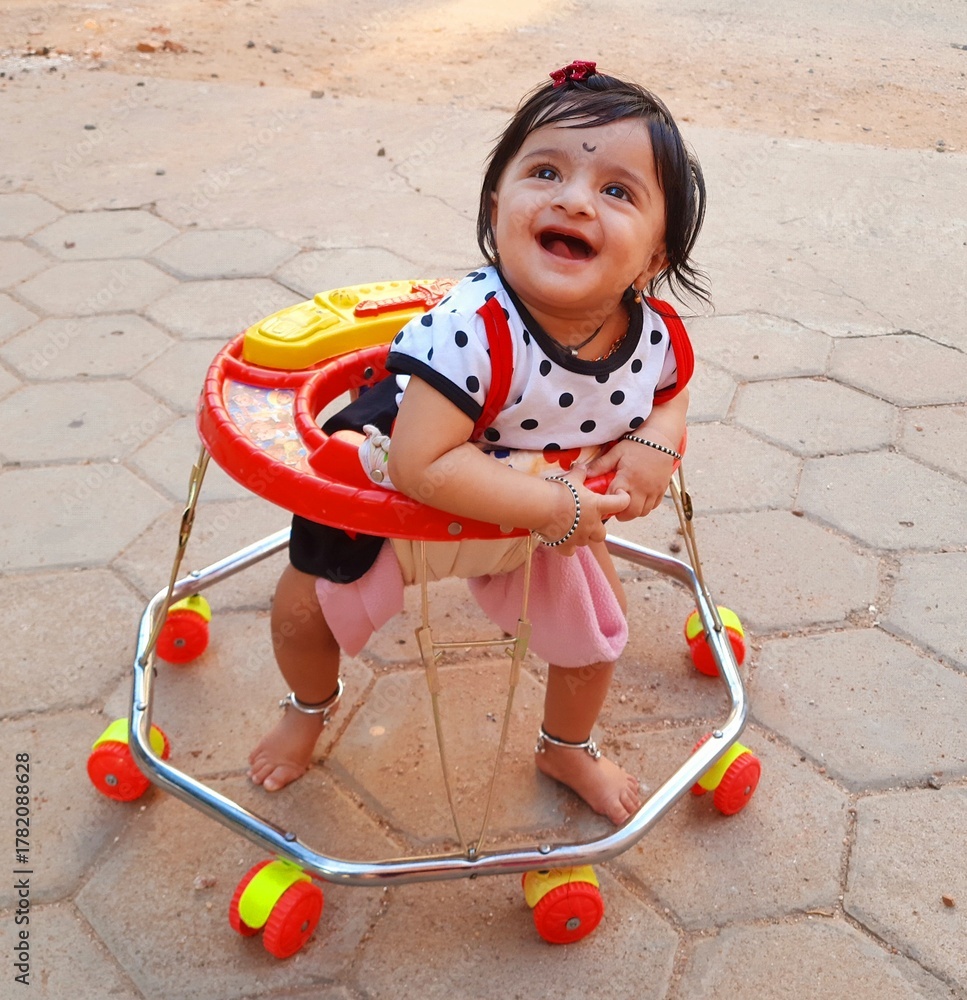 Fototapeta premium Little girl enjoying the baby walker for the first time starring at the sky with a joyous smile. 