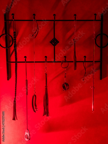 Collection of BDSM toys, whips in red light. 