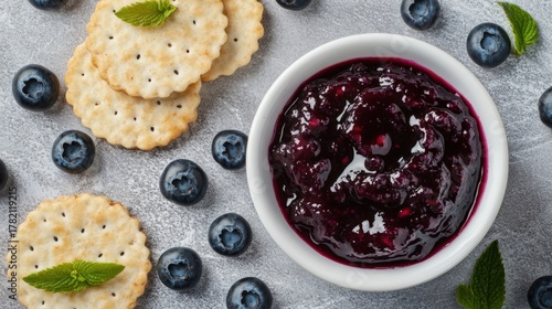 Blueberries in a white bowl with blueberry jam on a gray and white background top view