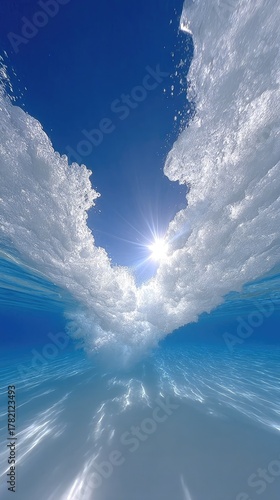 Close Up Underwater View Of Ocean Surface With Bright Sunlight Shining Through Foamy White Waves And Ripples On A Clear Blue Sky Background