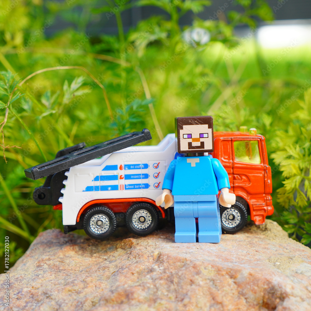 Obraz premium Minecraft Steve figure with toy tow truck on a rock outdoors