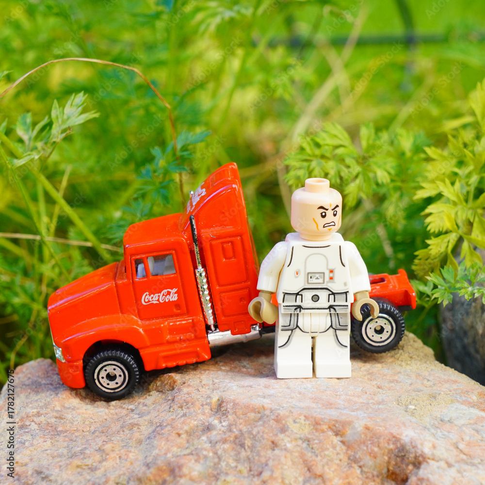 Naklejka premium Lego Star Wars figure stands beside a red Coca-Cola truck on a rock