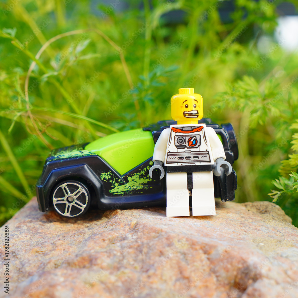 Obraz premium Lego astronaut figure standing next to a toy car on a rock