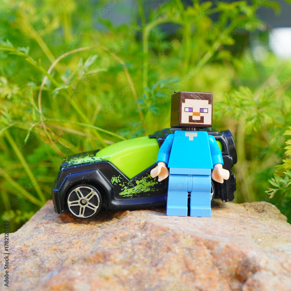 Naklejka premium Minecraft Steve figure with toy car on a rock in a natural setting