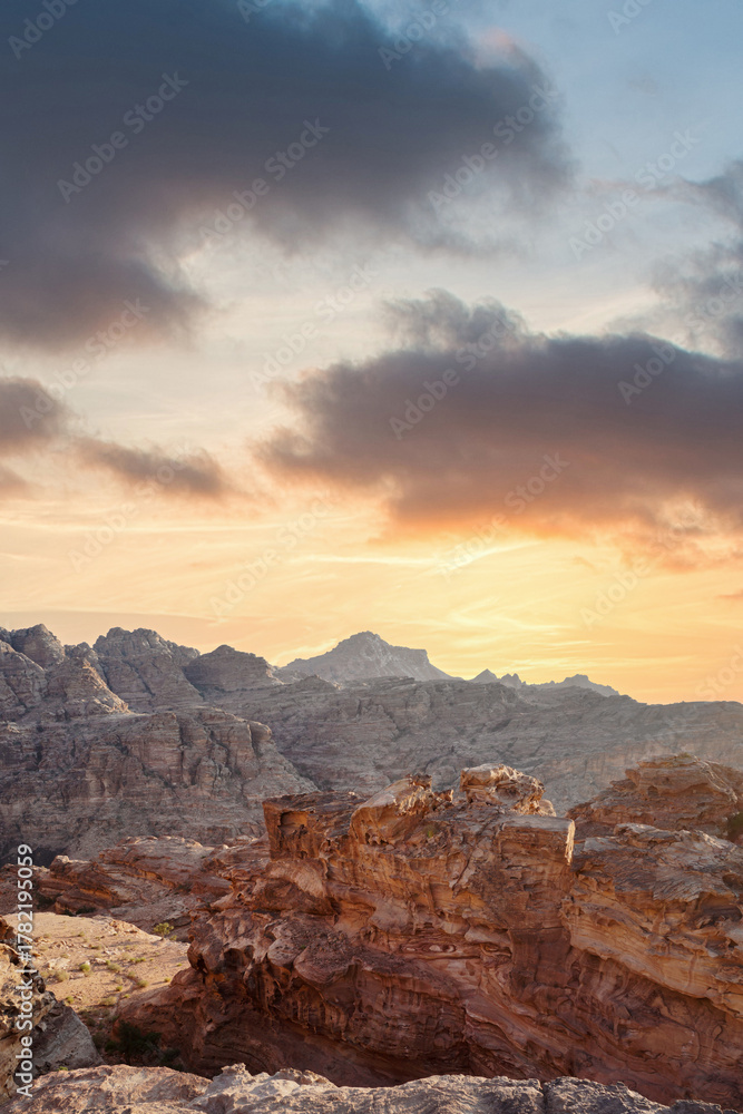 Fototapeta premium Sunset over rugged mountains showcasing dramatic rock formations and vibrant sky. Petra, jordan.