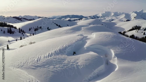 Wide snow-covered hills and trails under clear sky
