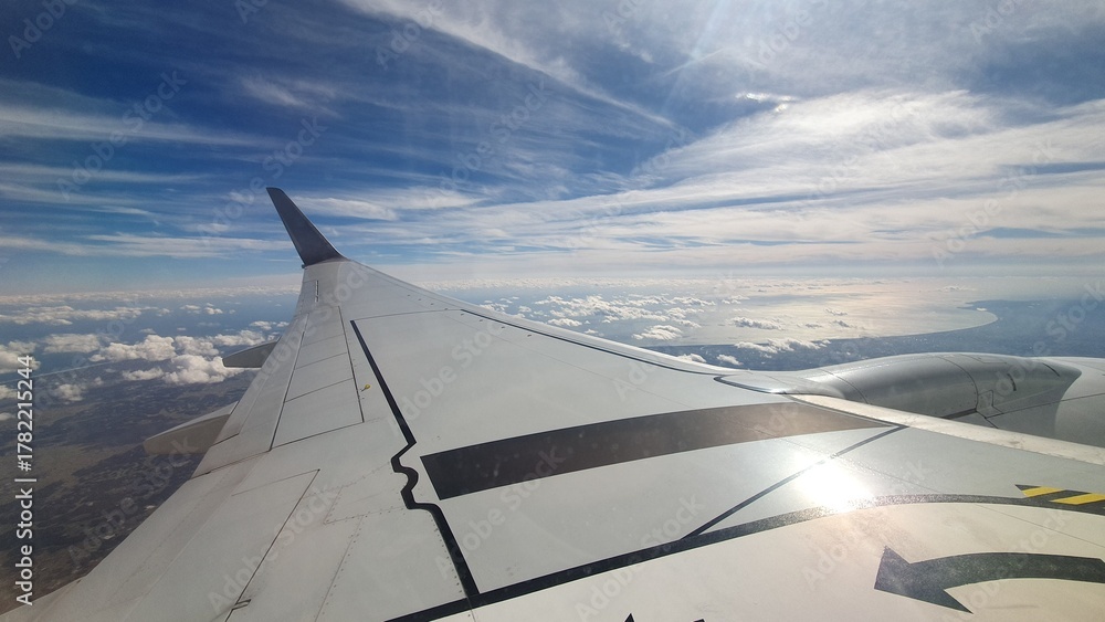 Obraz premium View from Airplane Window with Wing and Blue Sky