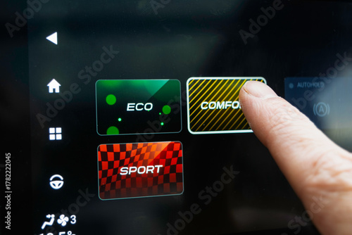 Finger taps car touchscreen driving mode menu showing ECO COMFORT SPORT, offering choice between efficiency, comfort and sport.