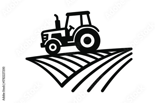Black and white farm tractor working on cultivated agricultural land rows