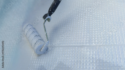 Painting waterproof resin on fiberglass mesh with roller tool