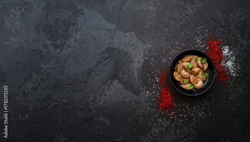 Fototapeta Naklejka Na Ścianę i Meble -  Food arranged on a dark backdrop, featuring scattered salt and red pepper flakes, highlighting spice mixture texture