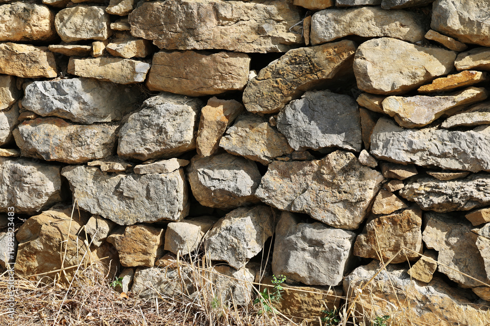 Fototapeta premium Natural stone wall as a fence in a field