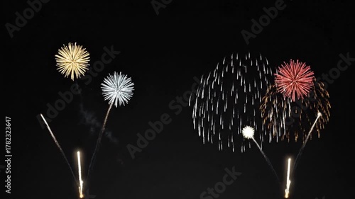 Dynamic explosions of shimmering golden, silver, and red fireworks lighting up the night, capturing the excitement of a grand pyrotechnic show