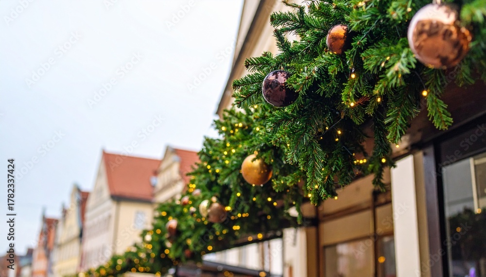 Fototapeta premium Christmas decorations on houses at the Christmas market in city. View of garlands, ornaments and fir branches