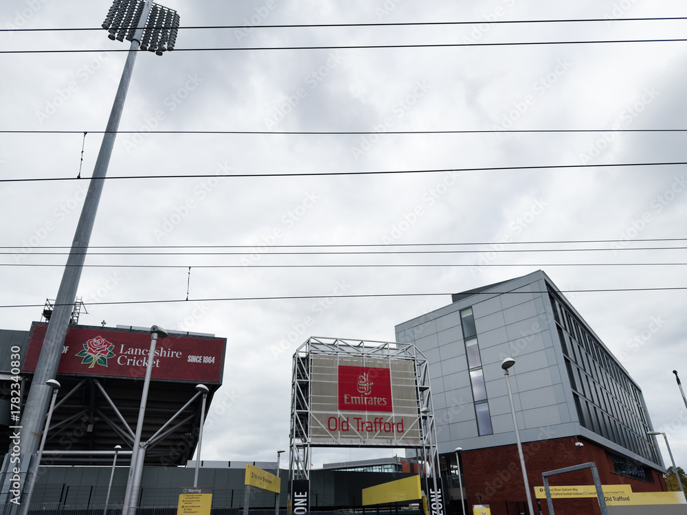 Fototapeta premium Manchester Old Trafford exterior with Emirates signage under cloudy sky and stadium lights