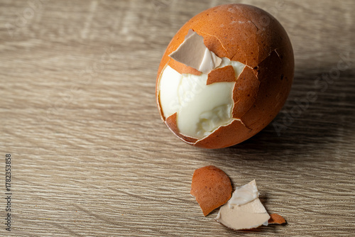 Canvastavla Close up of partially peeled boiled egg with shell fragments on rustic wooden surface