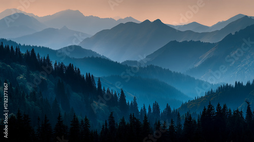 Layered mountain ranges with evergreen trees and a hazy blue atmosphere at dusk or dawn