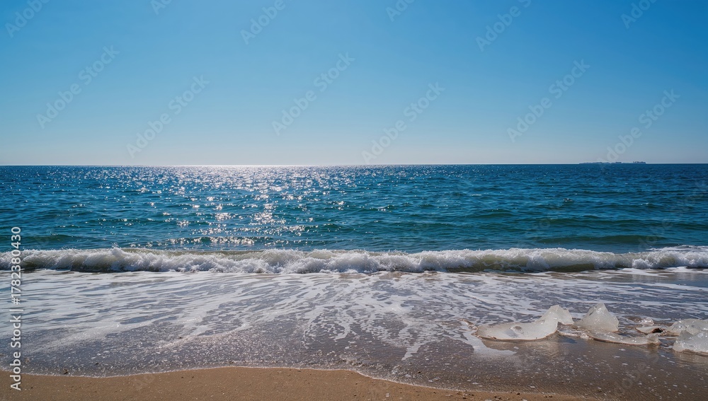 Obraz premium View over blue sea with shimmering small waves in spring sunshine, erosion risk