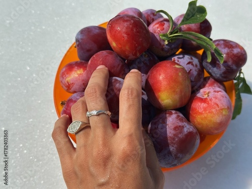 My hand Reaching for Fresh Plums in a Bowl, Naxos, Greece
