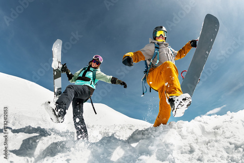 Two happy young snowboarders are having fun and jumps with snowboards from snowdrift. Winter vacations at ski resort concept