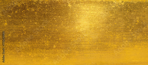 Gold wall texture background. Yellow shiny gold foil paint on wall sheet with gloss light reflection, vibrant golden paper luxury wallpaper