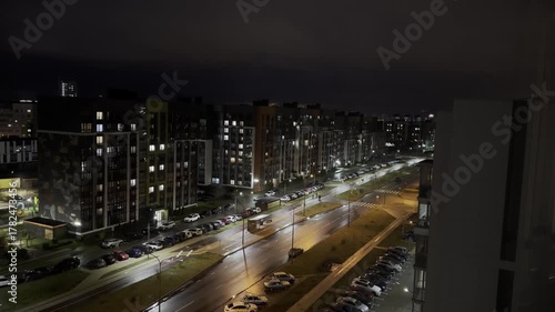 Street at night in quiet neighborhood, modern residential buildings with illumination, wet asphalt